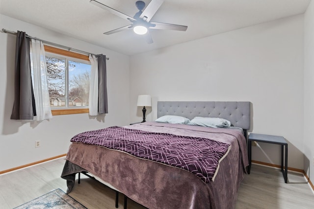 bedroom featuring a ceiling fan, baseboards, and wood finished floors