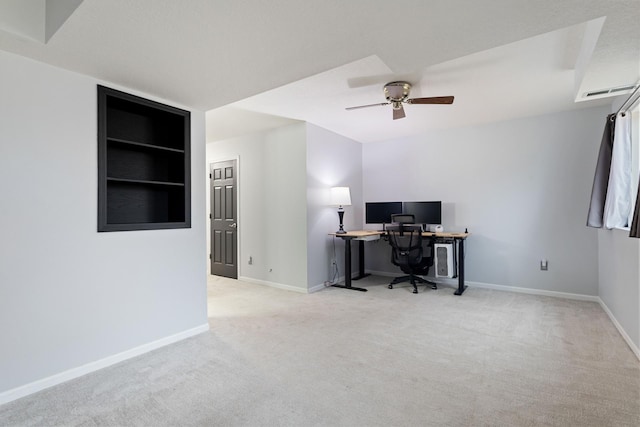 carpeted office space featuring ceiling fan and baseboards