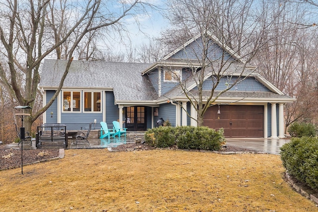 view of front facade featuring a garage, a front yard, roof with shingles, and driveway