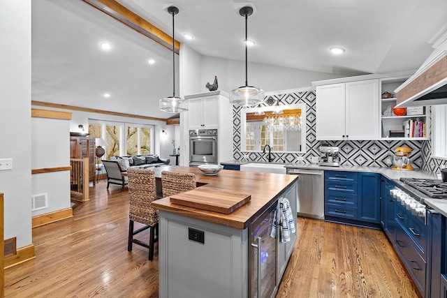 kitchen with visible vents, wood counters, appliances with stainless steel finishes, vaulted ceiling with beams, and blue cabinetry