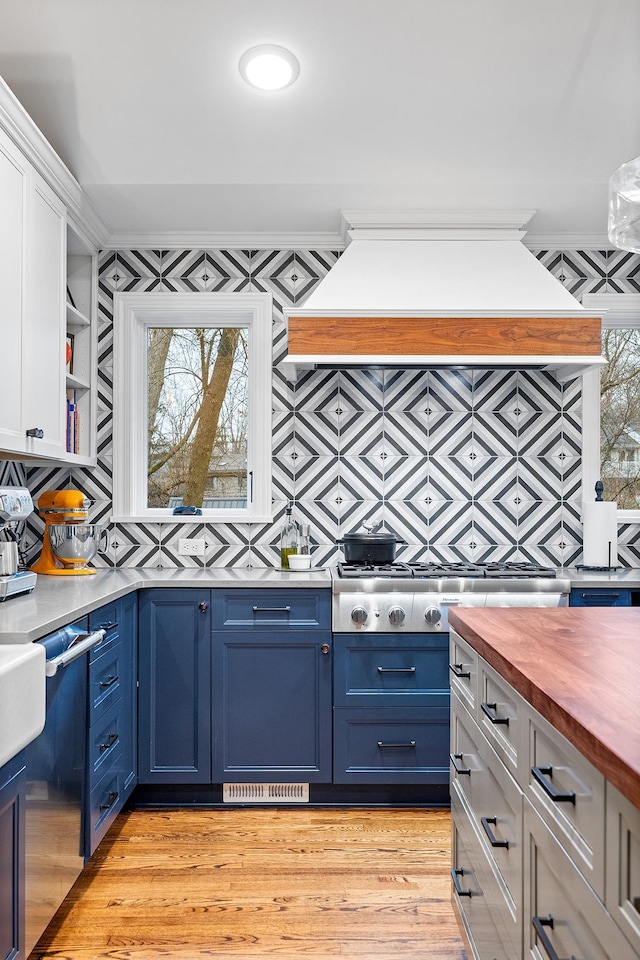 kitchen with butcher block counters, decorative backsplash, light wood-style floors, white cabinetry, and blue cabinets