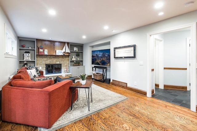 living room featuring built in shelves, a fireplace, recessed lighting, wood finished floors, and baseboards