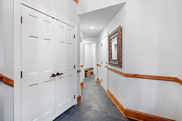 corridor with stone finish flooring and baseboards