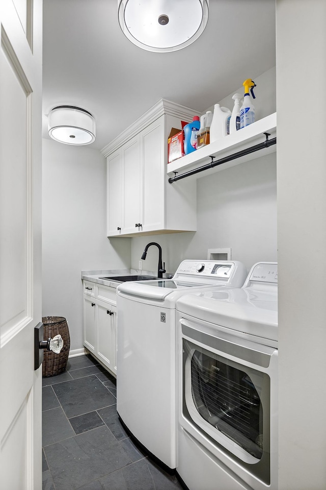 clothes washing area with cabinet space, stone finish flooring, a sink, independent washer and dryer, and baseboards