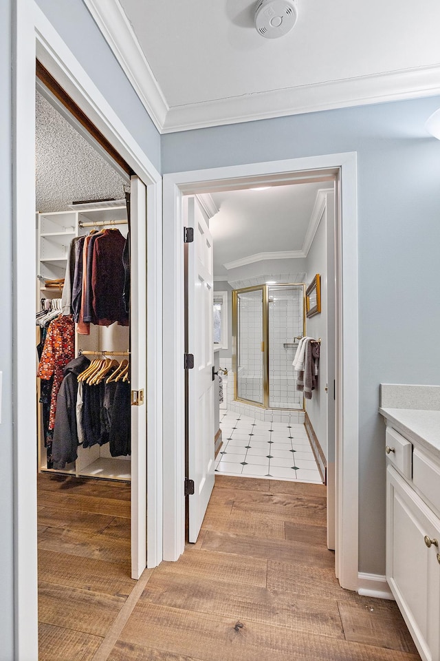 corridor with ornamental molding, light wood-style flooring, and baseboards