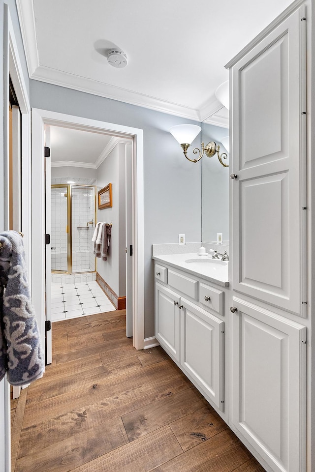 bathroom featuring a stall shower, ornamental molding, wood finished floors, and vanity