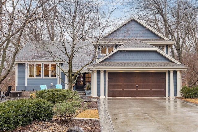 view of front facade with a garage, a shingled roof, and concrete driveway