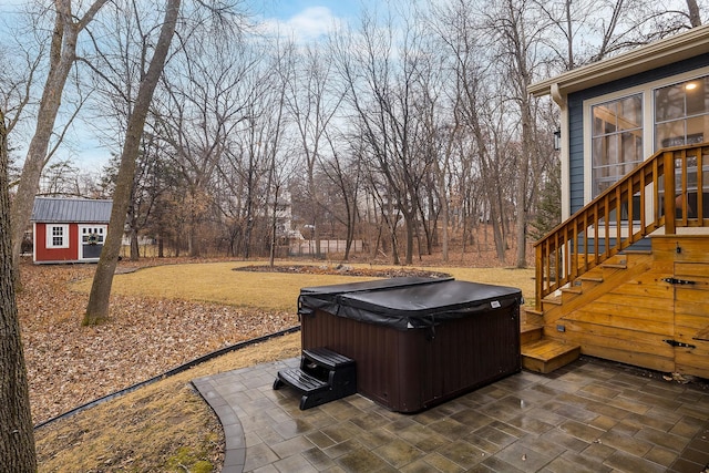 view of patio / terrace featuring a hot tub, stairway, and an outbuilding