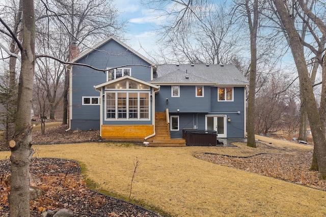 back of property with a sunroom, a hot tub, a shingled roof, and a yard