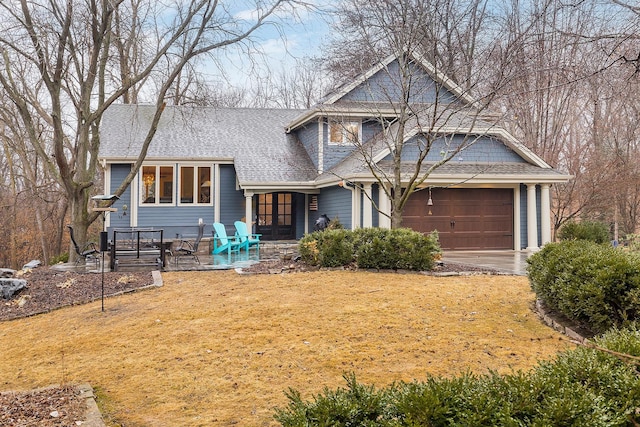 view of front of property featuring a garage, roof with shingles, and a front yard