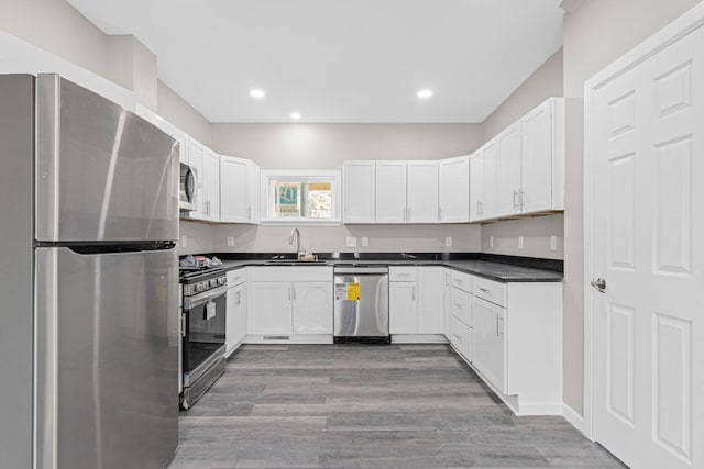 2310 Leona Dr, New Brighton, MN 55112 - kitchen with appliances with stainless steel finishes, dark countertops, recessed lighting, white cabinets, and light wood-style floors