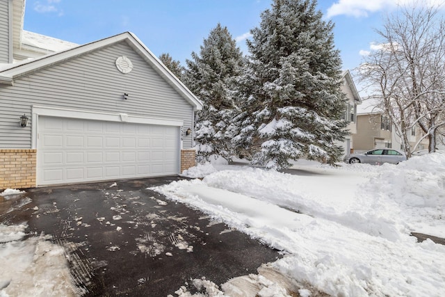 exterior space with brick siding, an attached garage, and aphalt driveway