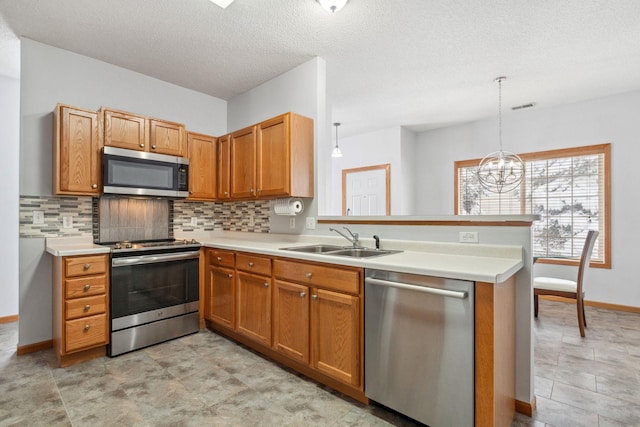 kitchen with a peninsula, a sink, light countertops, appliances with stainless steel finishes, and decorative backsplash