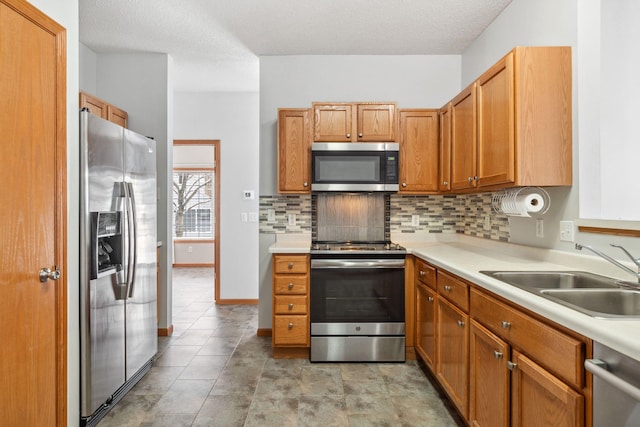 kitchen with decorative backsplash, stainless steel appliances, a sink, and light countertops