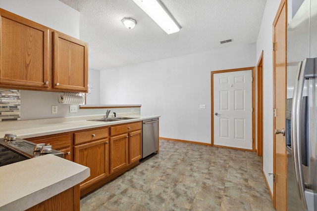 kitchen featuring appliances with stainless steel finishes, light countertops, visible vents, and a sink