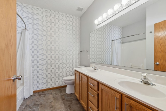 full bathroom with toilet, double vanity, a sink, and visible vents