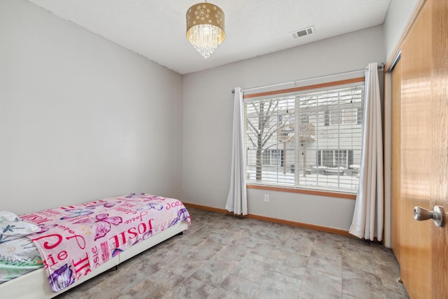 bedroom with visible vents, a notable chandelier, a textured ceiling, and baseboards