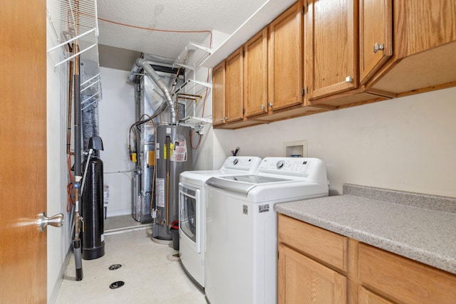 laundry room featuring cabinet space, a textured ceiling, gas water heater, and washer and dryer