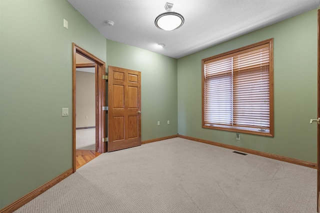 carpeted empty room featuring visible vents and baseboards