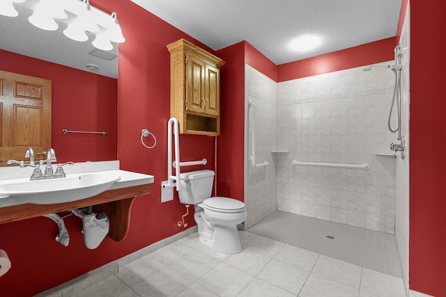 bathroom with a textured ceiling, tile patterned flooring, toilet, baseboards, and tiled shower