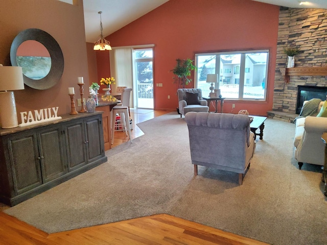 living room with high vaulted ceiling, a chandelier, a fireplace, and wood finished floors