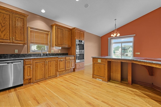 10590 Alamo St NE, Blaine, MN 55449 - kitchen with appliances with stainless steel finishes, light wood-type flooring, dark countertops, brown cabinets, and vaulted ceiling