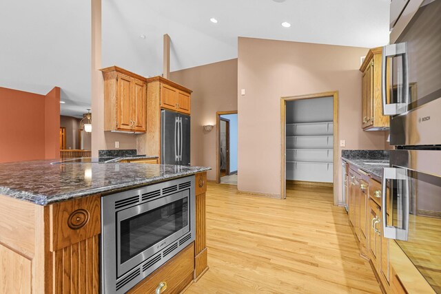 10590 Alamo St NE, Blaine, MN 55449 - kitchen with stainless steel appliances, light wood-style flooring, dark stone counters, high vaulted ceiling, and baseboards