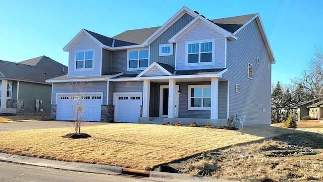 craftsman house featuring a garage, driveway, a front lawn, and board and batten siding