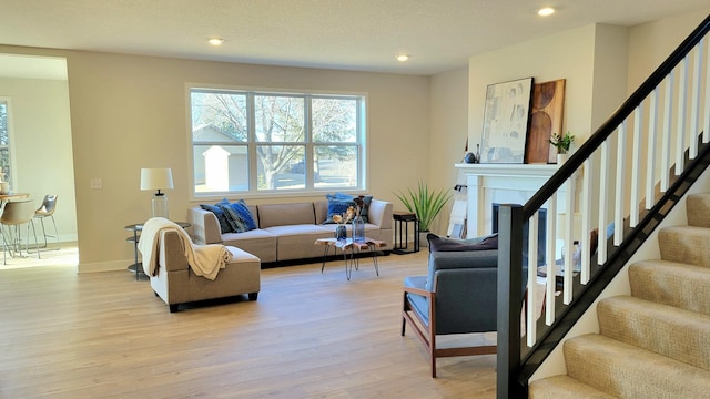 living area featuring recessed lighting, stairway, light wood-style floors, a textured ceiling, and baseboards