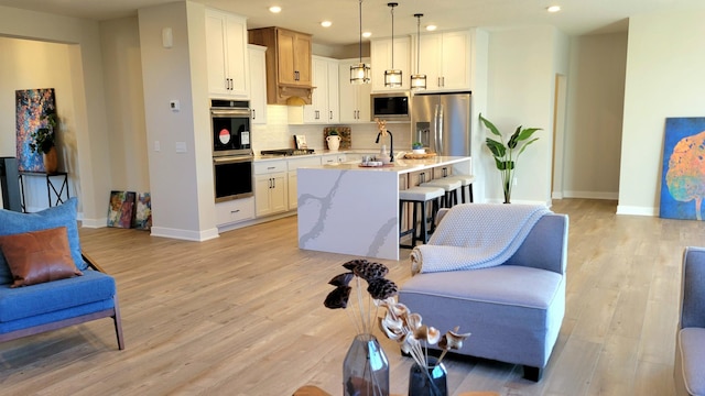 kitchen featuring open floor plan, stainless steel appliances, a breakfast bar, and light wood-style floors