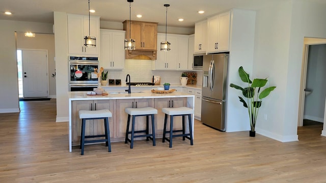 kitchen featuring light wood-type flooring, appliances with stainless steel finishes, light countertops, and a breakfast bar area