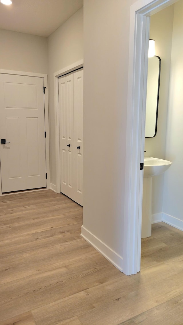 hall featuring light wood-style floors and baseboards