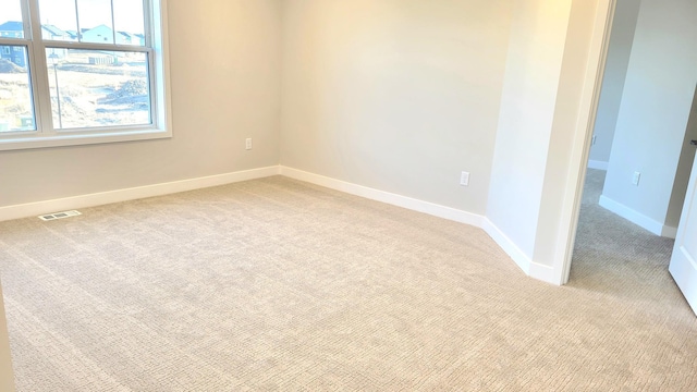 spare room with visible vents, light carpet, and baseboards