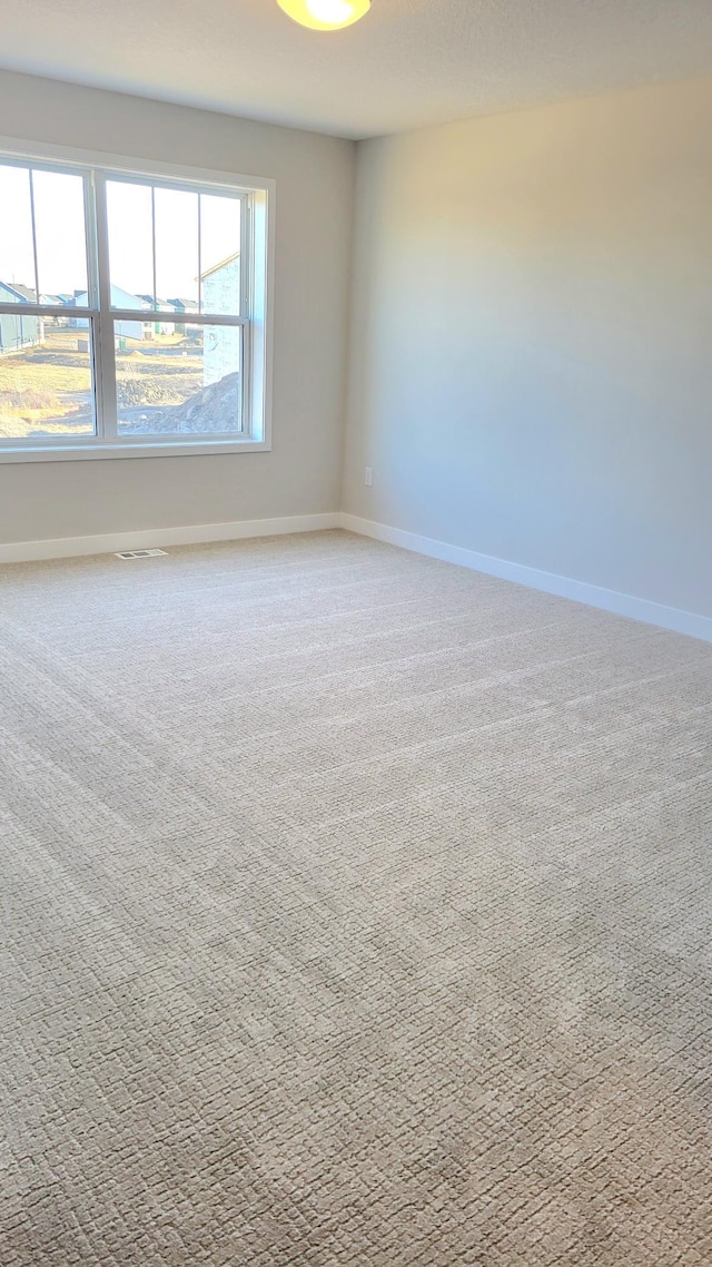 carpeted empty room with baseboards and visible vents