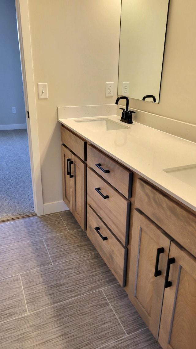 bathroom featuring double vanity, baseboards, and a sink