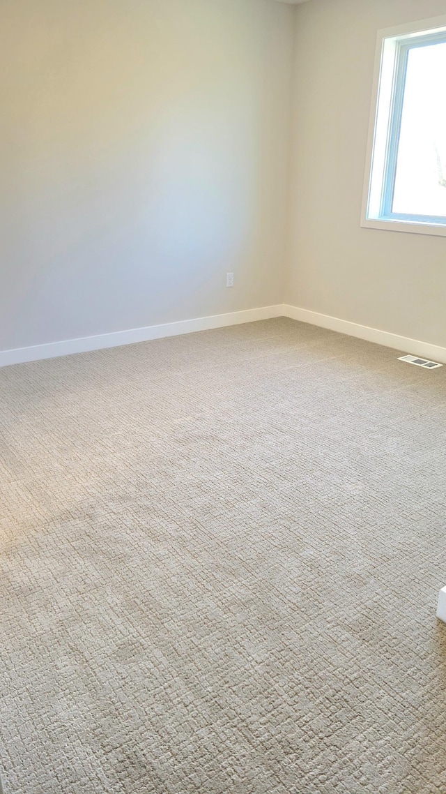 carpeted empty room with visible vents and baseboards