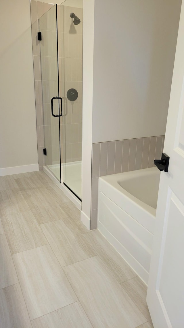 full bathroom featuring a stall shower, baseboards, and a bath