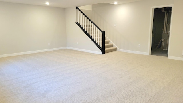 empty room with stairs, recessed lighting, light colored carpet, and baseboards