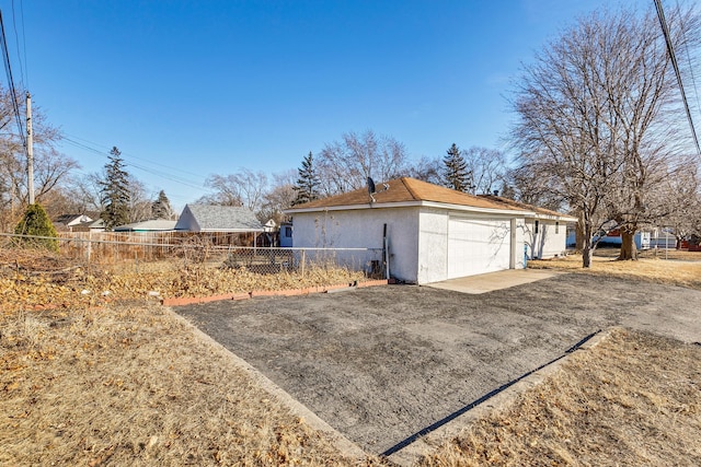 view of property exterior with driveway, fence, and stucco siding