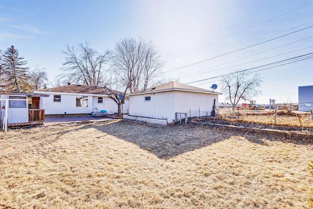 back of property featuring fence, an outdoor structure, and stucco siding