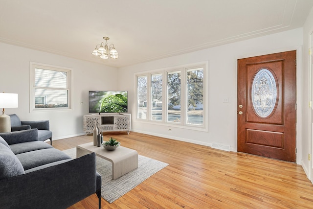 living room with a chandelier, light wood finished floors, visible vents, and baseboards