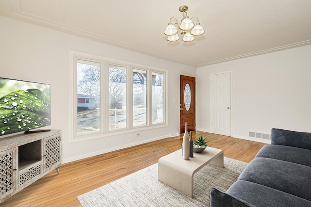 living area featuring an inviting chandelier, baseboards, visible vents, and wood finished floors