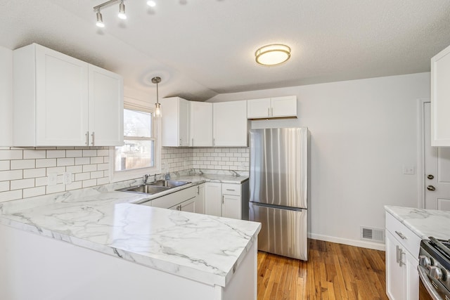 kitchen with visible vents, decorative backsplash, appliances with stainless steel finishes, white cabinetry, and a sink