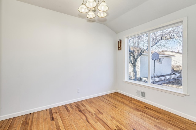 spare room with light wood-type flooring, baseboards, visible vents, and a notable chandelier