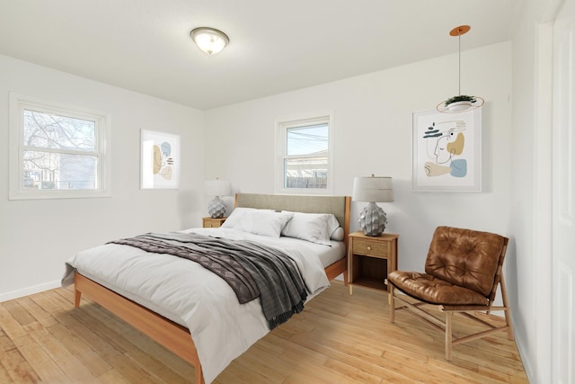 bedroom with baseboards, multiple windows, and light wood finished floors