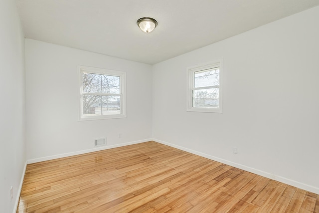 spare room with light wood-style floors, baseboards, and visible vents