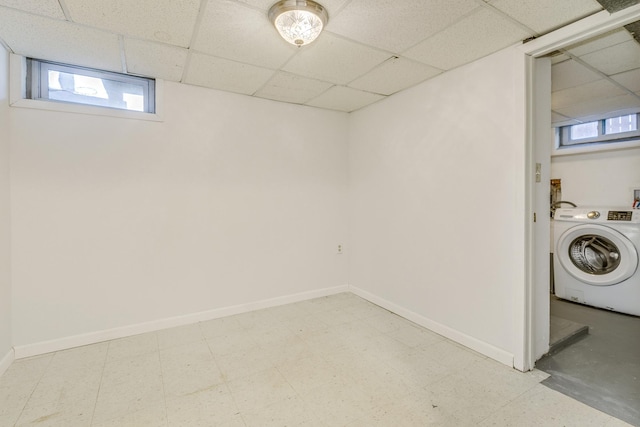 basement featuring light floors, washer / clothes dryer, a drop ceiling, and baseboards