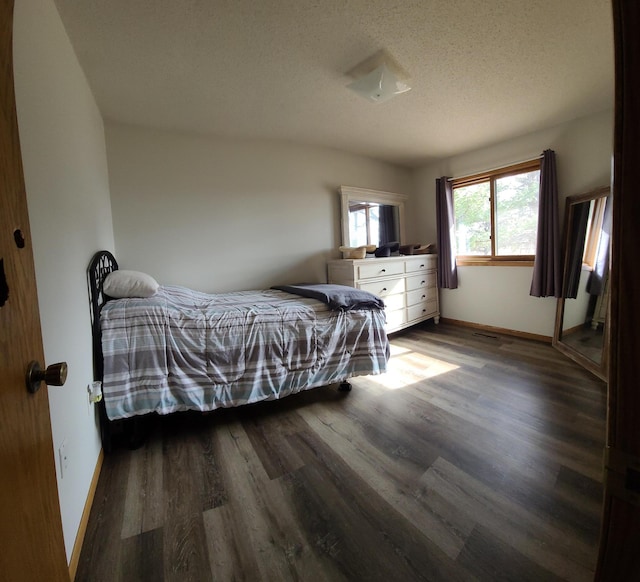 bedroom featuring baseboards, a textured ceiling, and dark wood finished floors