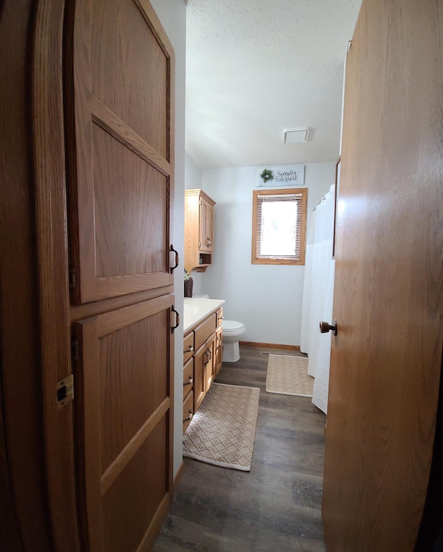 bathroom featuring visible vents, toilet, vanity, wood finished floors, and a textured ceiling