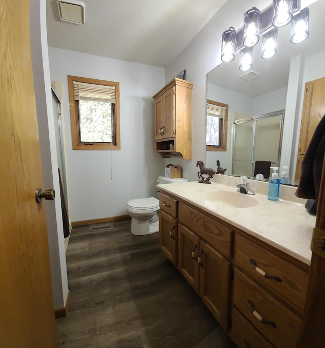 full bathroom with toilet, wood finished floors, a shower stall, baseboards, and vanity